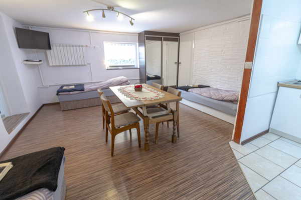 Duży pokój z 3 łóżkami, stołem i aneksem kuchennym