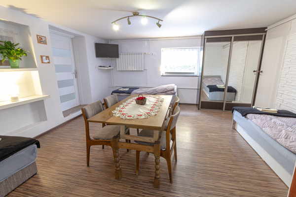 Duży pokój z 3 łóżkami, telewizorem i szafą komandor